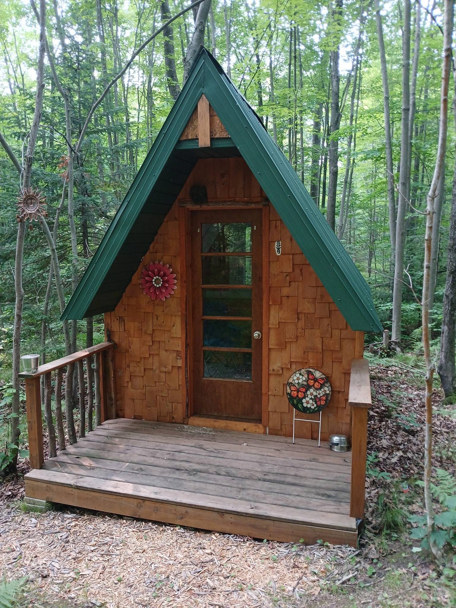 The Whooping Crane cabin, cedar-shingled with a green roof and a wooden deck