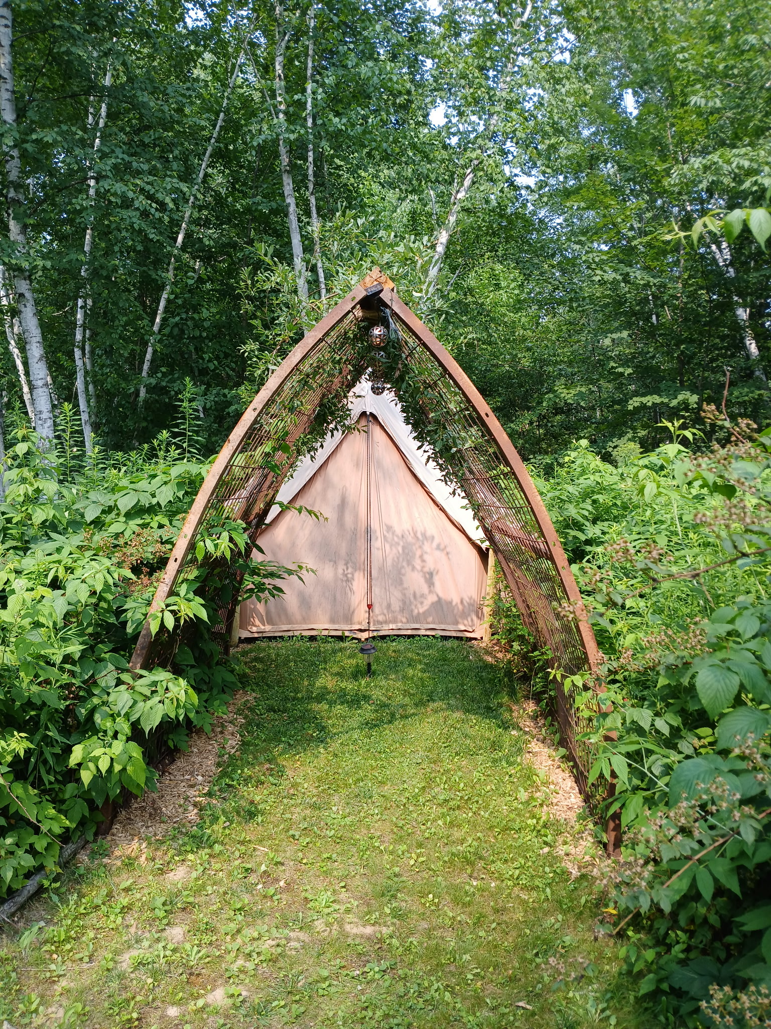 The Wood Turtle Yurt, a canvas bell tent framed by the tall iron arch